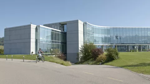 Femme à vélo devant le bâtiment UCB à Bulle
